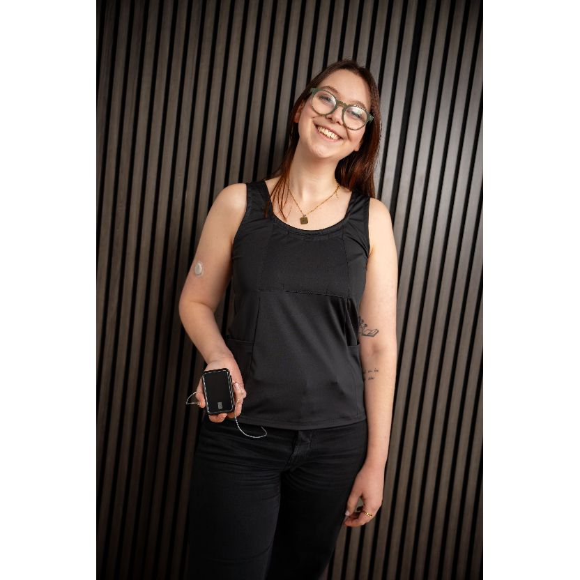 Person wearing a black sleeveless top and black pants against a striped background