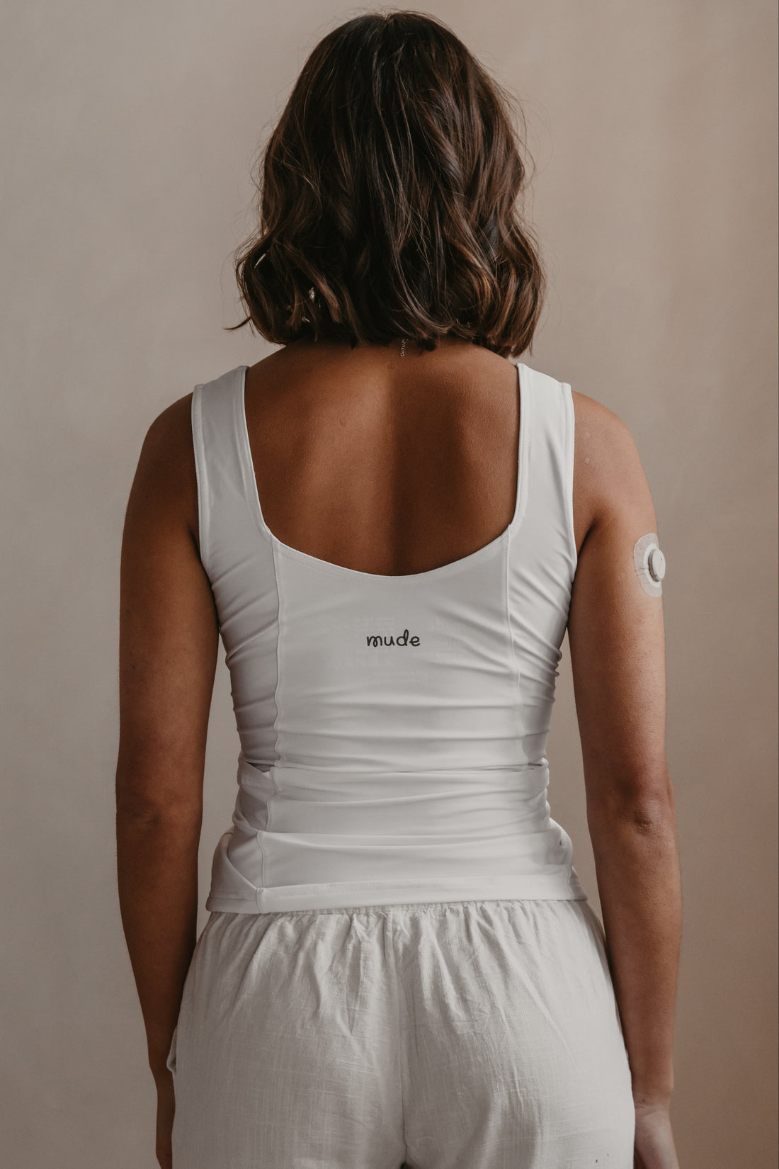Person wearing a white Mude tank top with &