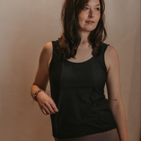 Woman wearing a black Mude Tank top against a beige background